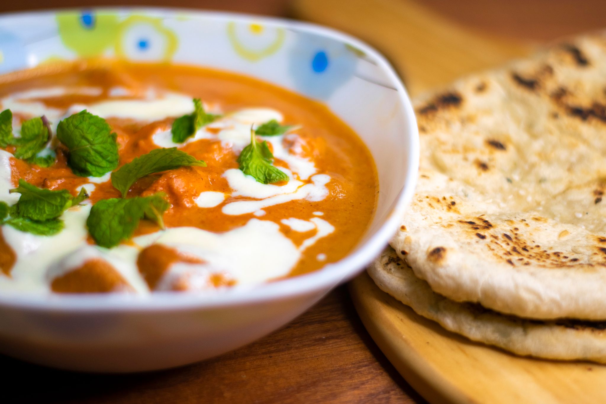 Delicious Indian butter chicken served with naan bread, garnished with fresh mint leaves.