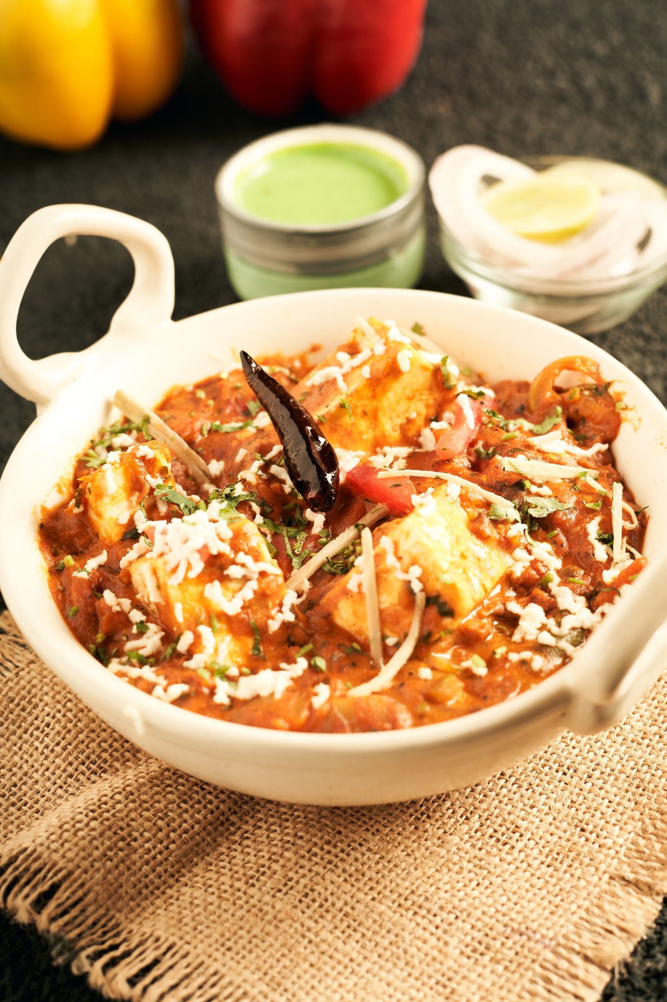 Delicious Indian paneer curry with spices and fresh herbs served in a white bowl.